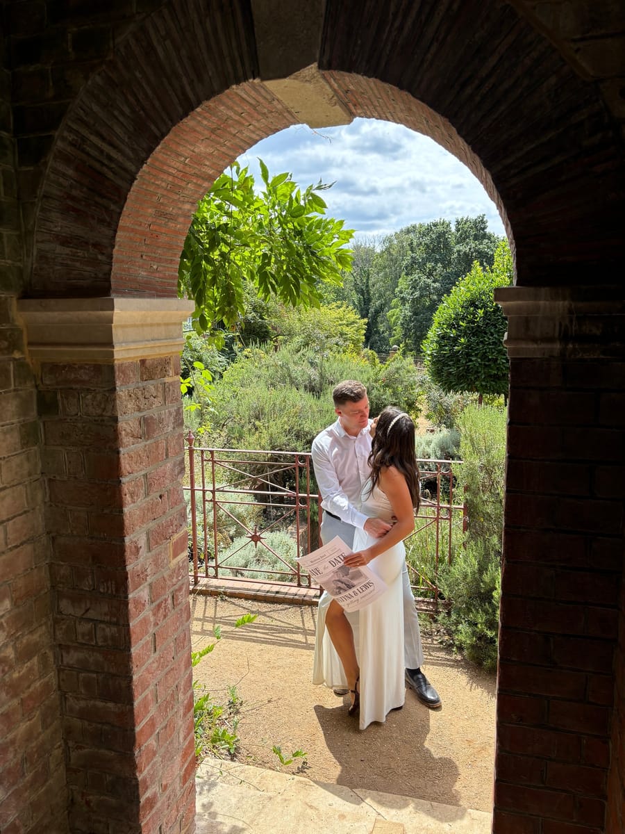 Justyna and Lewis in a garden, framed by a brick archway